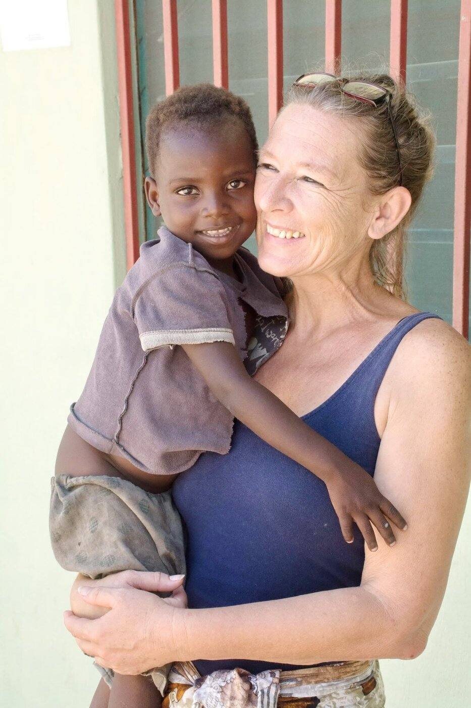 Barbara Hofmann holding a young child outside an ASEM facility in Mozambique.